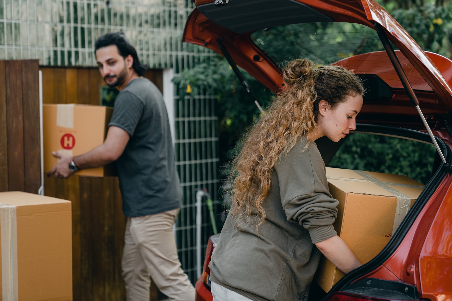 young couple unpacking car in yard of new house