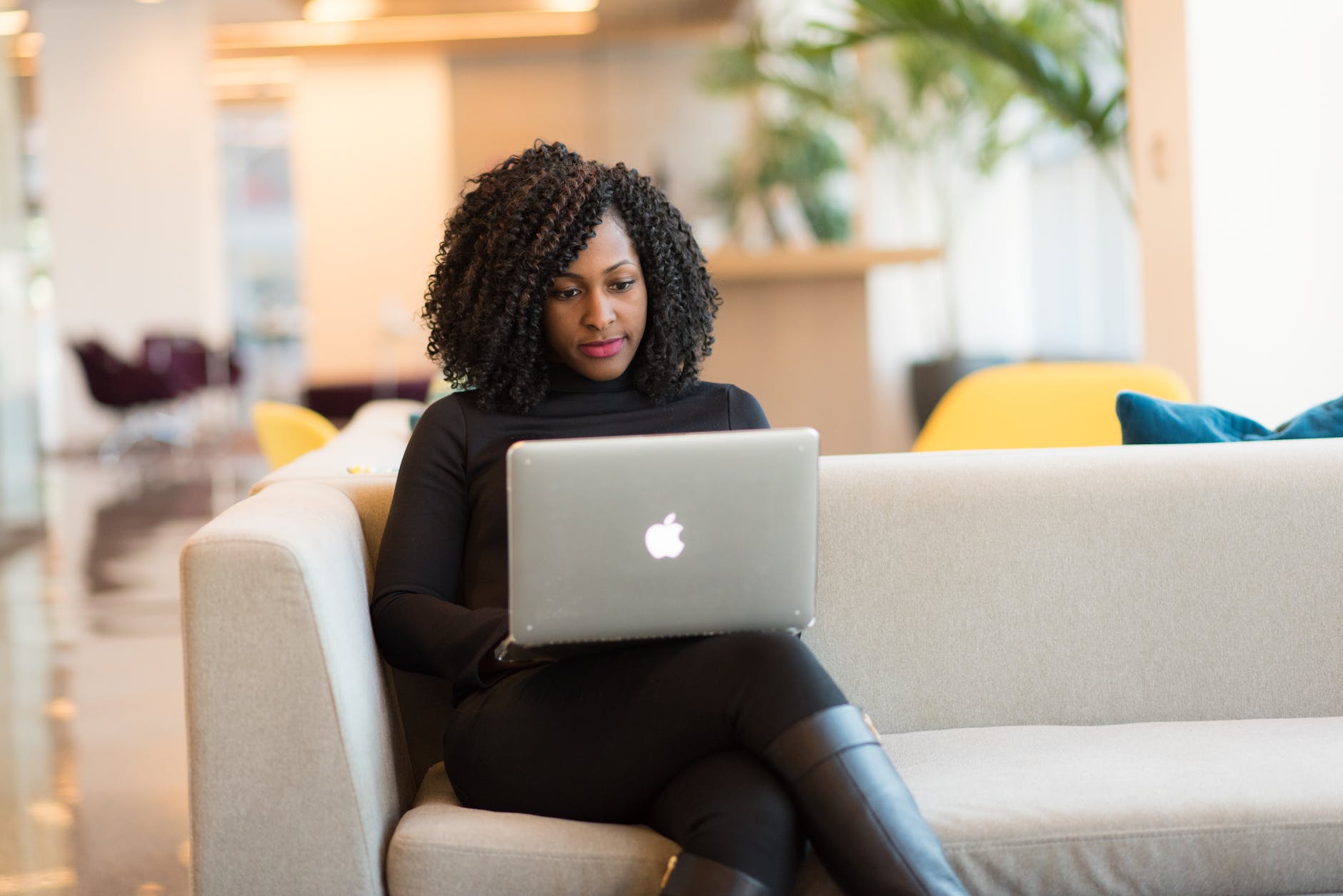 woman using macbook sitting on white couch